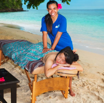 A staff member smiling while massaging a guest