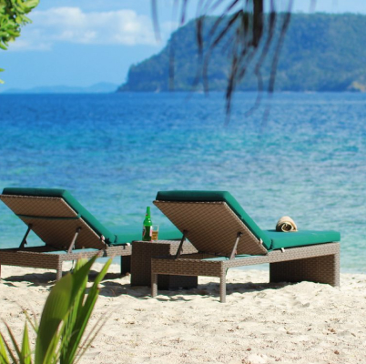 Two seat facing the ocean with a beer bottle on a table between them